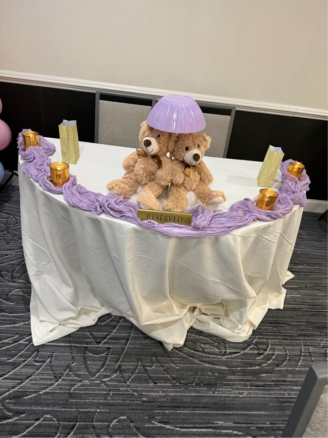 Baby shower cake table draped in lavender with teddy bear centerpiece